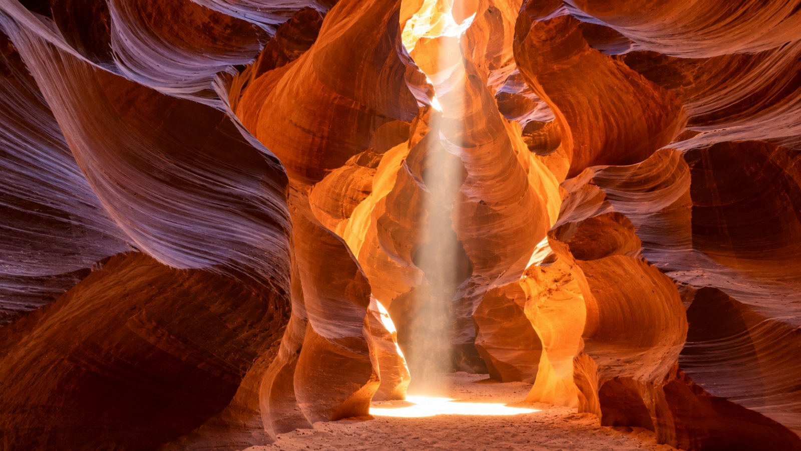 L'interno dell'Antelope Canyon con le pareti di arenaria ondulate e un fascio di luce che scende dall'alto