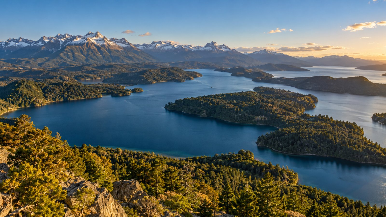 Il lago Nahuel Huapi visto dall'alto del Cerro Campanario, con penisole boscose, isole e montagne innevate sullo sfondo