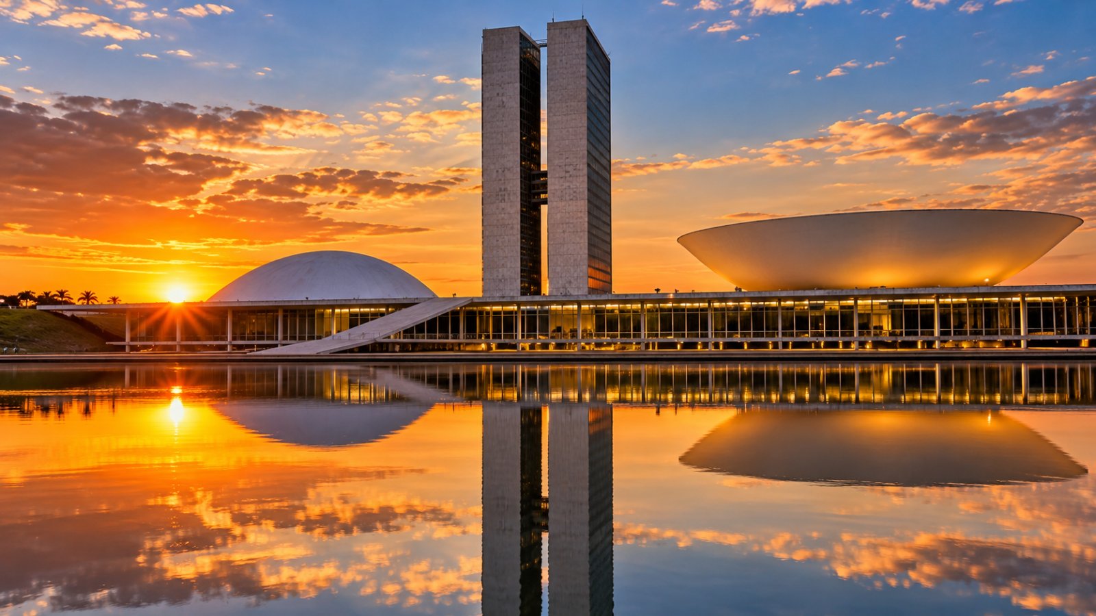 Il Congresso Nazionale di Brasília al tramonto: le due torri gemelle e le due cupole, una rivolta verso l'alto e una verso il basso, riflesse in una vasca d'acqua