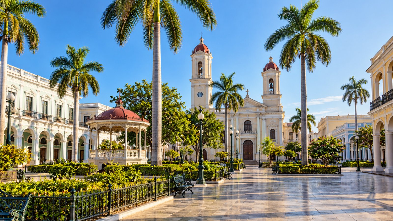 Il Parque José Martí di Cienfuegos con il gazebo, le palme reali, gli edifici con i porticati e la cattedrale dalle due torri