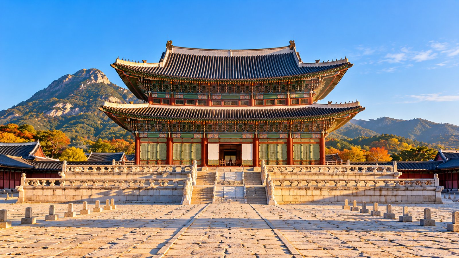 Il padiglione del trono Geunjeongjeon del palazzo Gyeongbokgung a Seul, con i tetti curvi dipinti e le montagne alle spalle, in una limpida mattina d'autunno