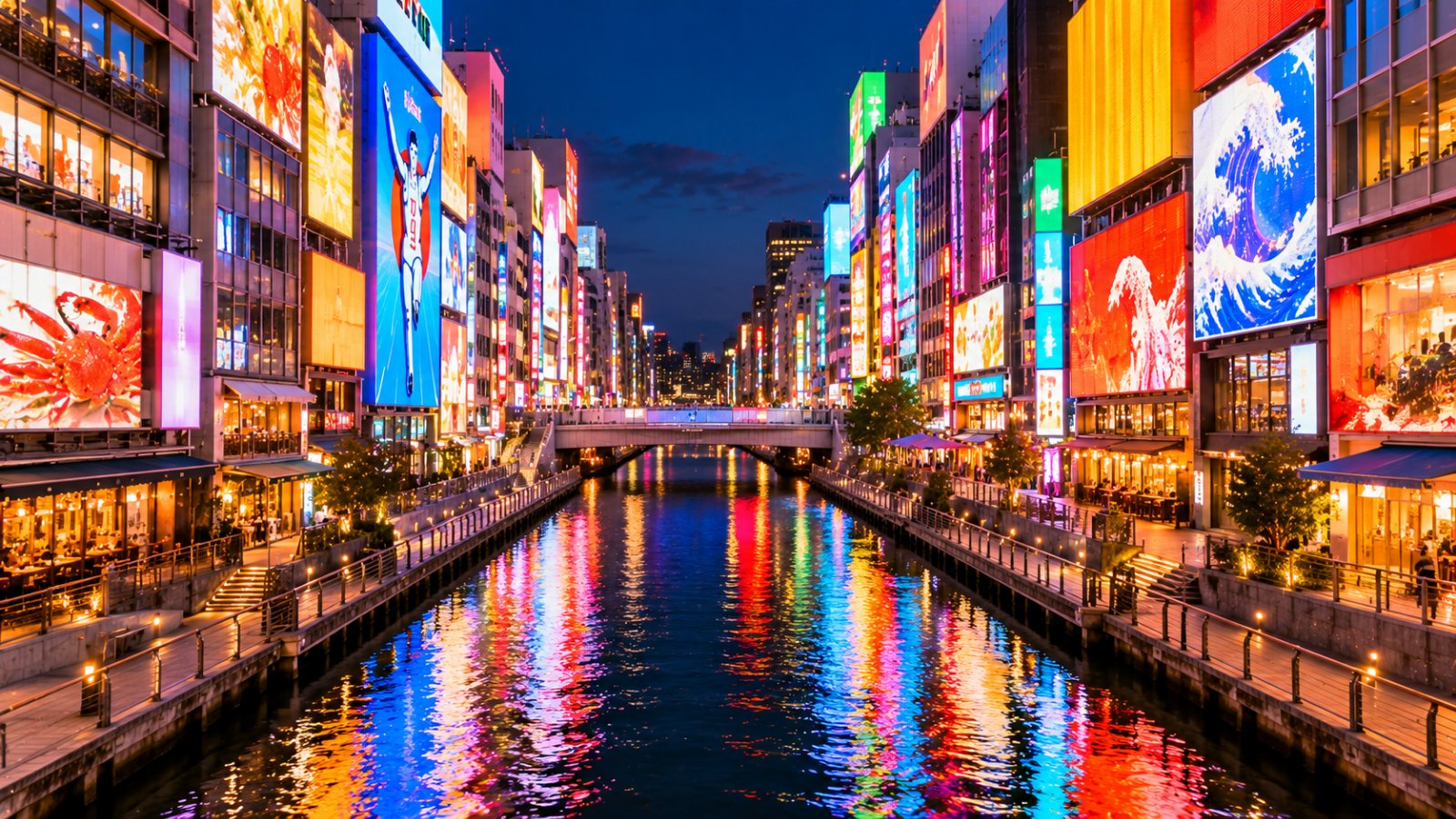 Il canale di Dotonbori a Osaka di sera, con le facciate dei palazzi coperte di grandi insegne luminose colorate riflesse nell'acqua