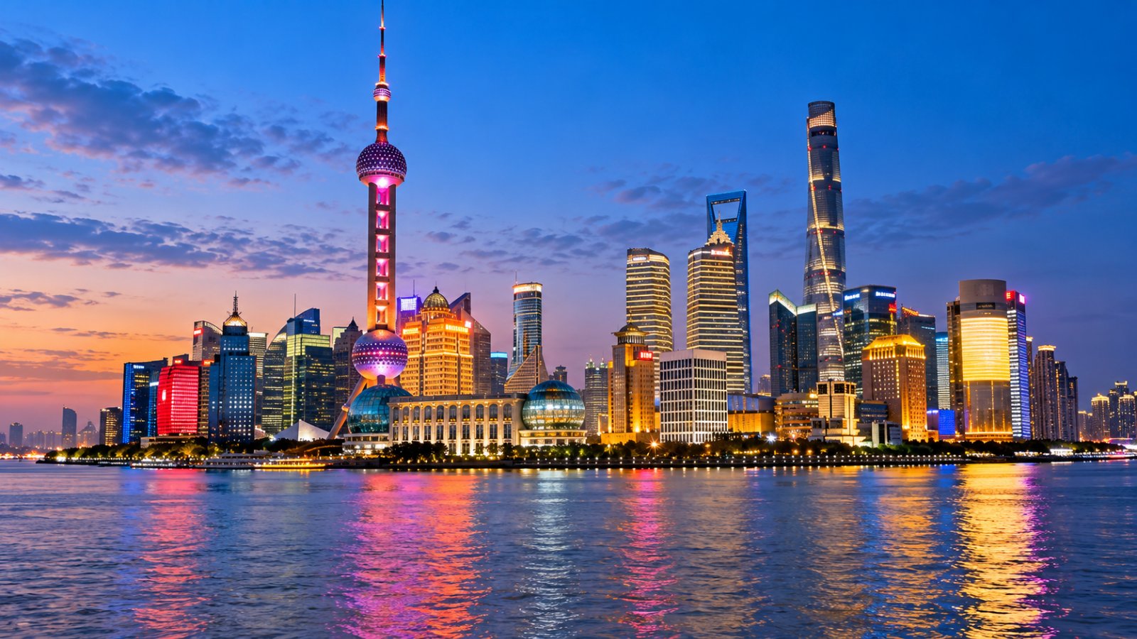 I grattacieli illuminati di Pudong con la Torre della Perla d'Oriente, riflessi nel fiume Huangpu all'ora blu