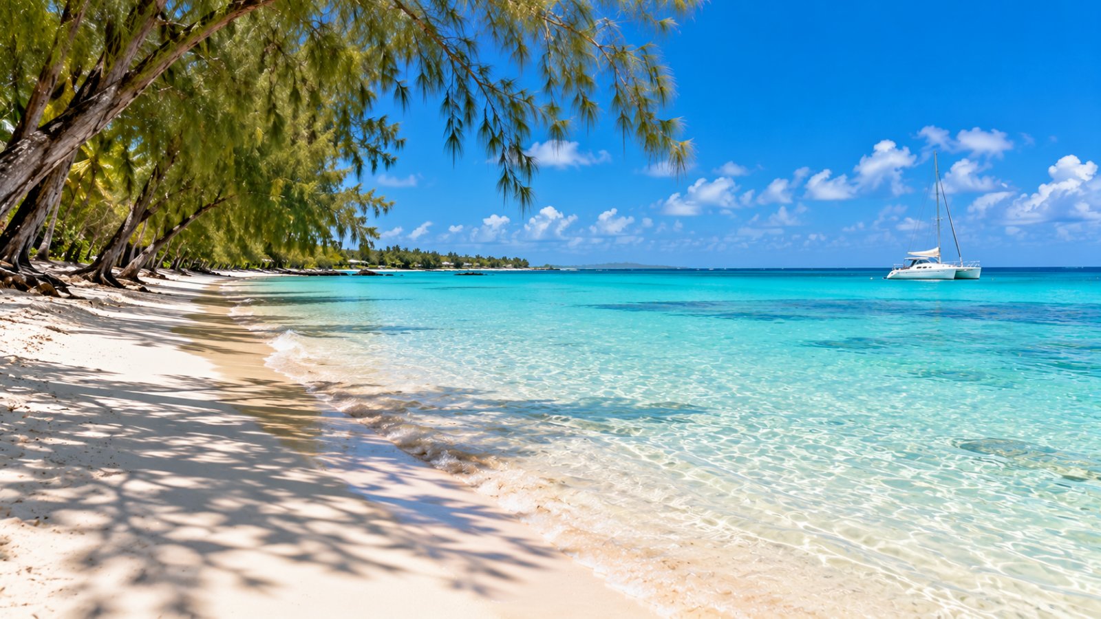 La laguna limpida di Trou aux Biches con la sabbia bianca, le casuarine e un catamarano all'orizzonte, sulla costa nord-ovest di Mauritius